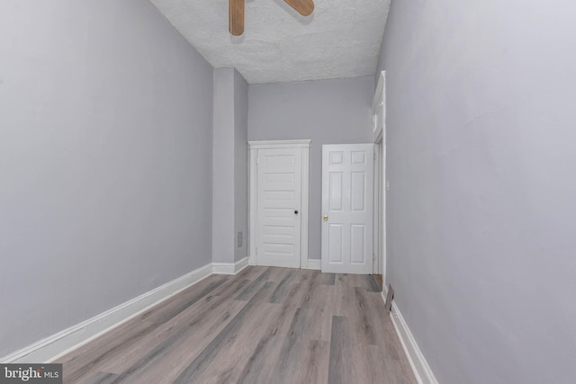 unfurnished room with ceiling fan, wood finished floors, baseboards, and a textured ceiling