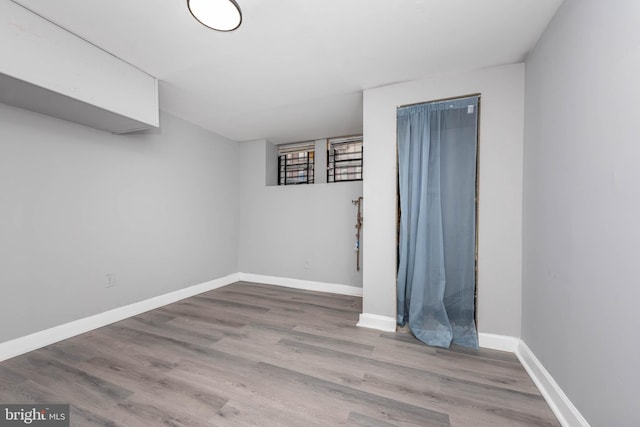 spare room with baseboards and wood finished floors
