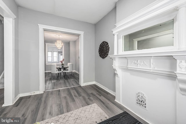 hall featuring baseboards, a notable chandelier, and wood finished floors