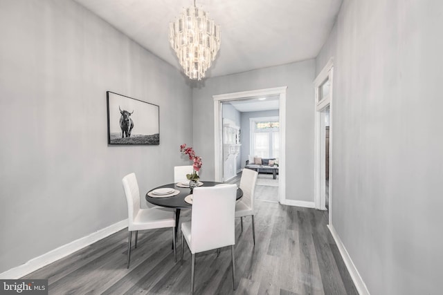 dining space with baseboards, an inviting chandelier, and wood finished floors