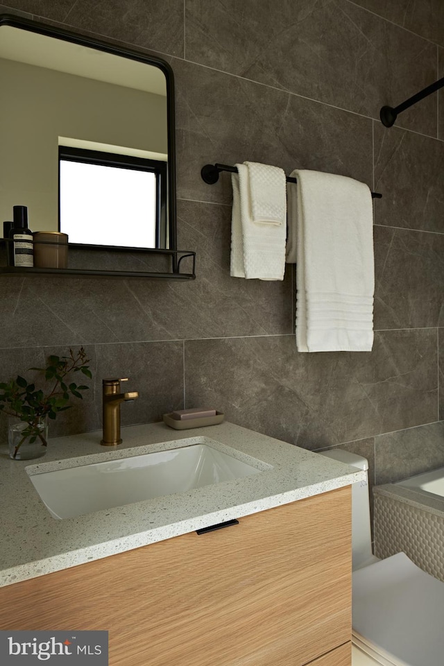 full bath with decorative backsplash, a tub to relax in, tile walls, and vanity