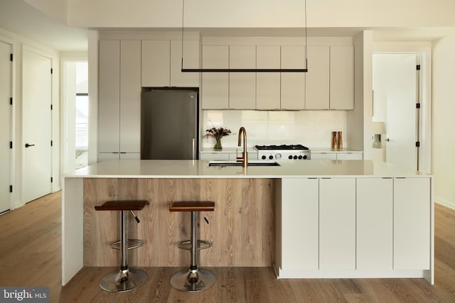 kitchen featuring a sink, modern cabinets, light wood-style flooring, and freestanding refrigerator