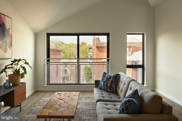 living room with baseboards, lofted ceiling, and wood finished floors