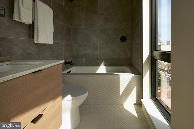 full bath with tiled shower / bath, toilet, tile walls, and vanity