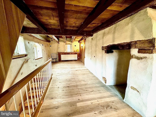 hall featuring beamed ceiling, light wood-style flooring, wood ceiling, and radiator heating unit