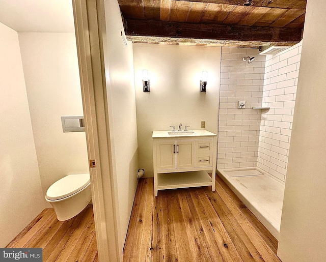 full bath with hardwood / wood-style flooring, beamed ceiling, toilet, and a shower stall