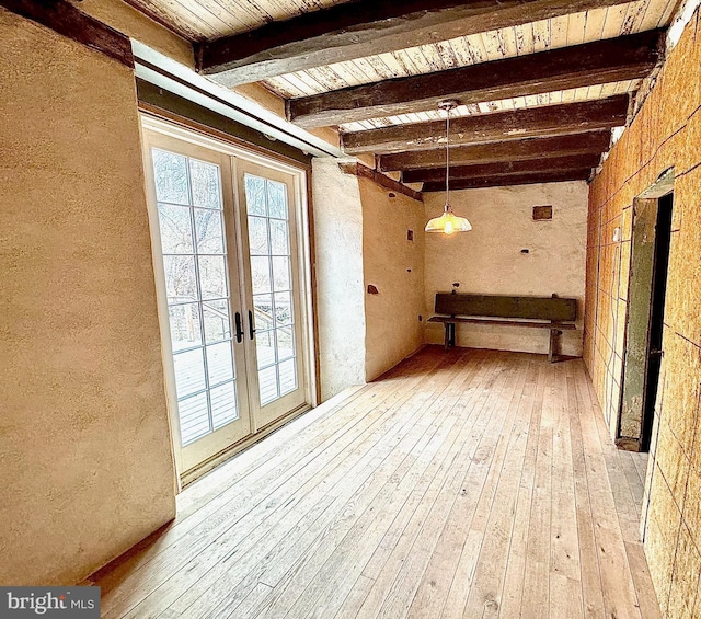 unfurnished dining area featuring wood ceiling, french doors, beamed ceiling, and light wood finished floors