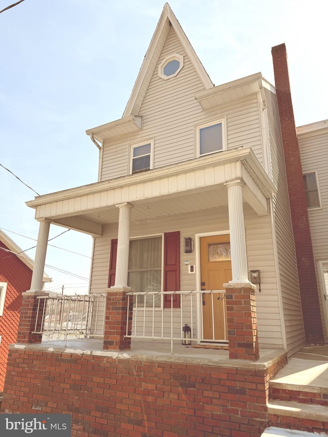 view of front facade with covered porch and a chimney