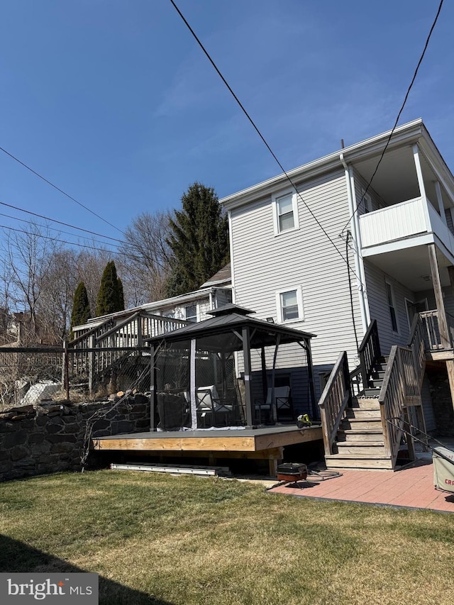 back of house featuring fence, a wooden deck, stairs, a gazebo, and a yard