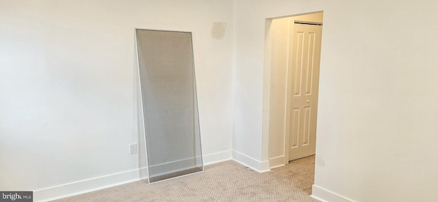 spare room with light colored carpet and baseboards