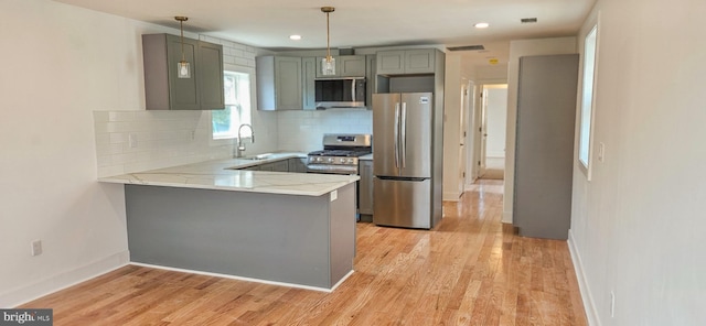 kitchen featuring gray cabinets, appliances with stainless steel finishes, a peninsula, and a sink