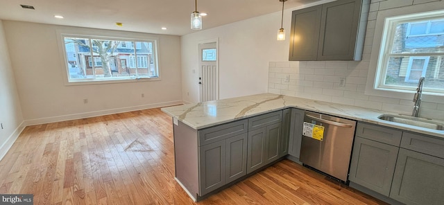 kitchen featuring gray cabinetry, a sink, stainless steel dishwasher, light wood finished floors, and a healthy amount of sunlight