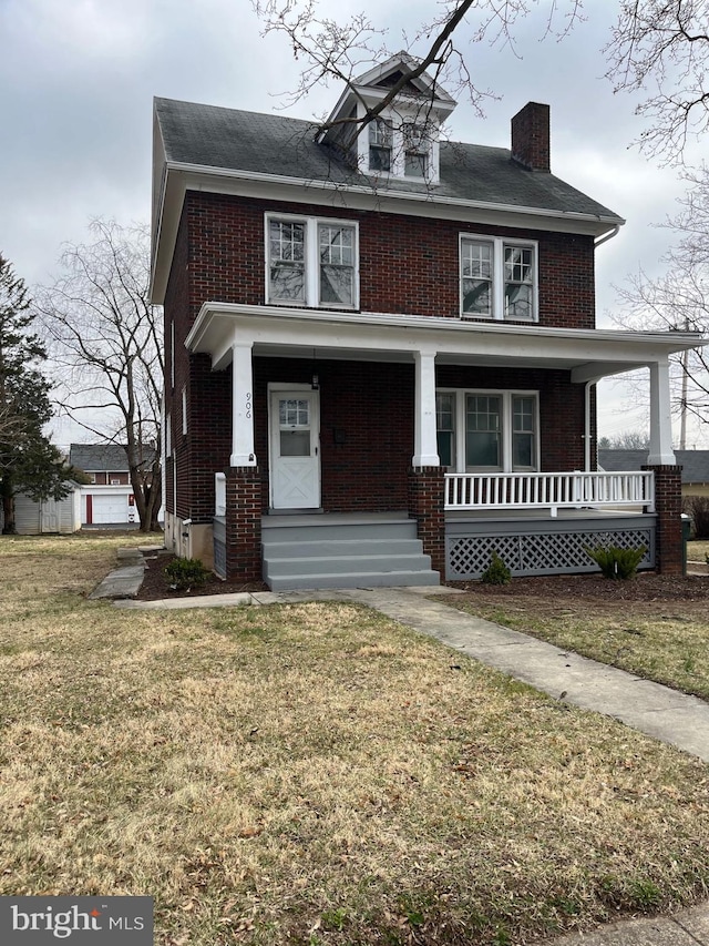 traditional style home featuring brick siding, a porch, a chimney, and a front yard