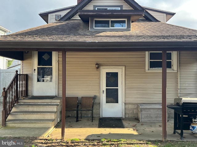 view of exterior entry with roof with shingles