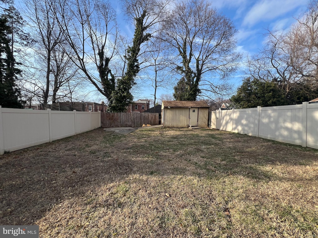 view of yard with a fenced backyard, a storage shed, and an outdoor structure