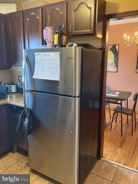 kitchen with light tile patterned floors, a notable chandelier, light countertops, and freestanding refrigerator