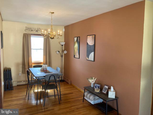 dining room with a baseboard heating unit, wood finished floors, an inviting chandelier, baseboards, and baseboard heating