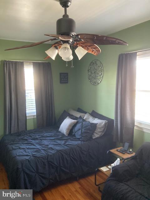 bedroom with a ceiling fan, lofted ceiling, and wood finished floors