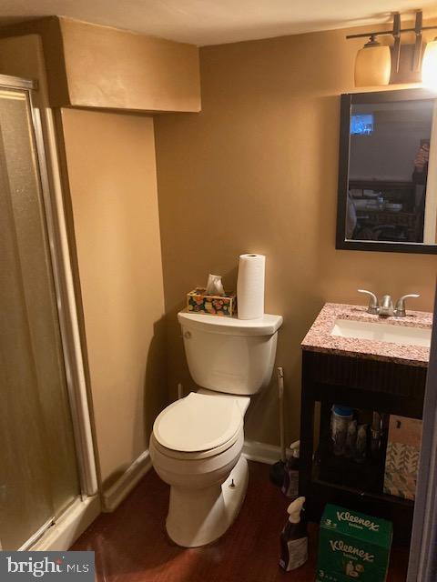 full bath featuring baseboards, toilet, a stall shower, and vanity