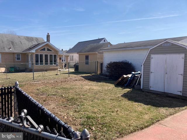 exterior space with a storage shed, a lawn, fence, and an outdoor structure