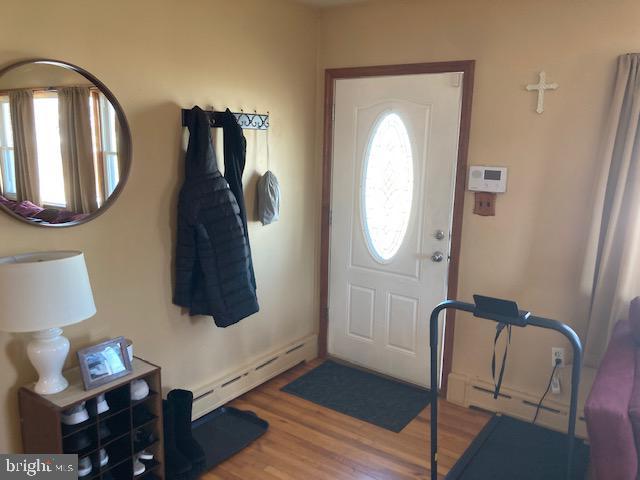 foyer entrance featuring a baseboard heating unit and wood finished floors