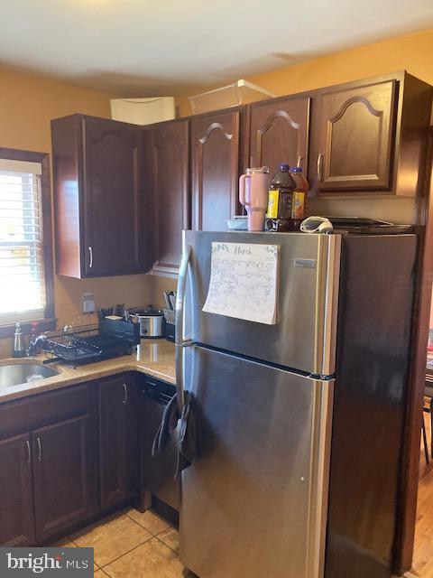 kitchen featuring light tile patterned floors, light countertops, freestanding refrigerator, and a sink