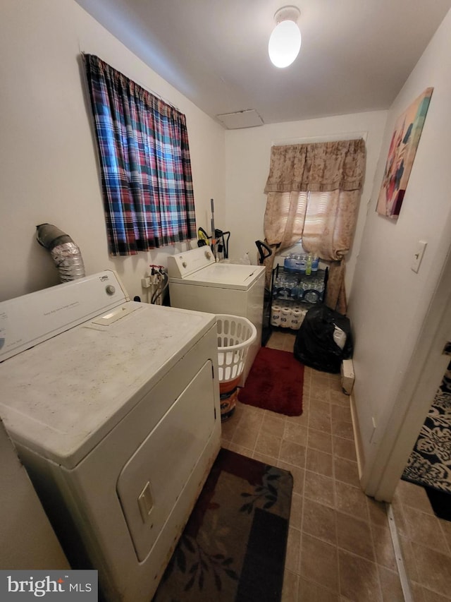 laundry area featuring laundry area, washing machine and dryer, baseboards, and tile patterned floors