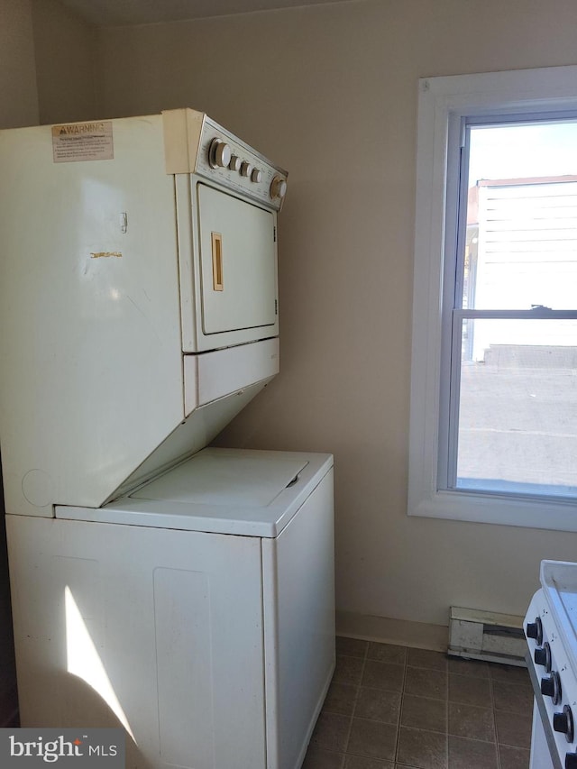 laundry area featuring laundry area, plenty of natural light, stacked washer and clothes dryer, and a baseboard radiator