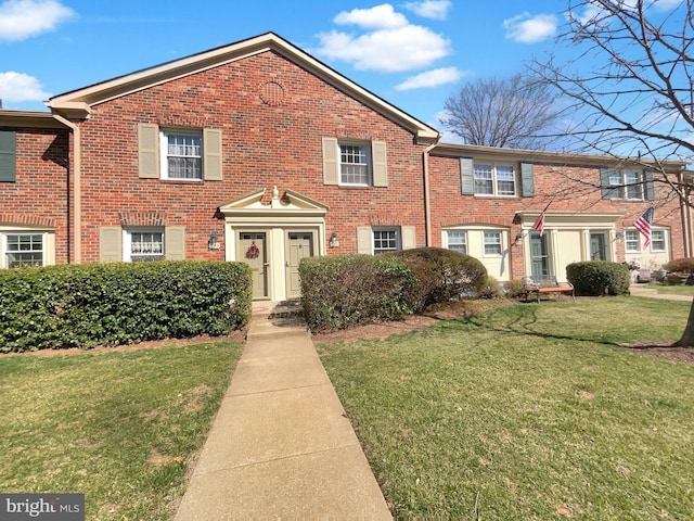 multi unit property with brick siding and a front yard