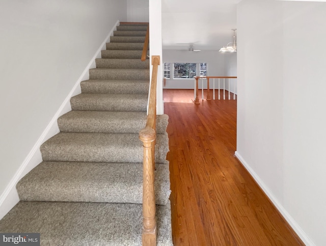 staircase with baseboards and wood finished floors