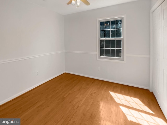 empty room featuring wood finished floors, baseboards, and ceiling fan