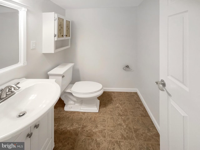 half bath with baseboards, toilet, and vanity