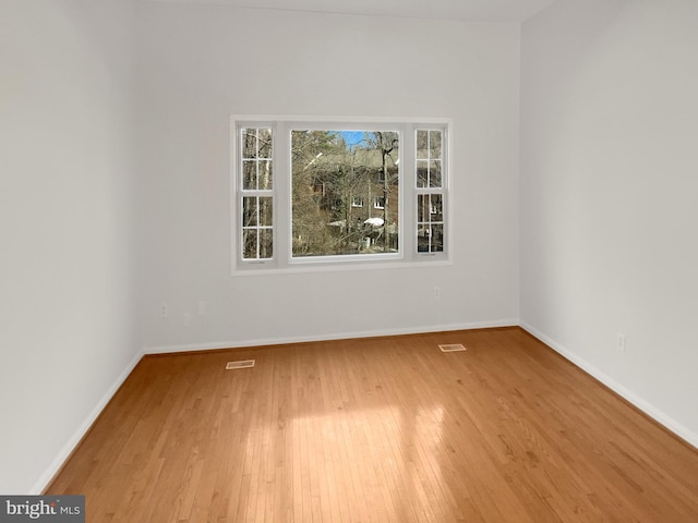 unfurnished room featuring hardwood / wood-style floors, baseboards, and visible vents