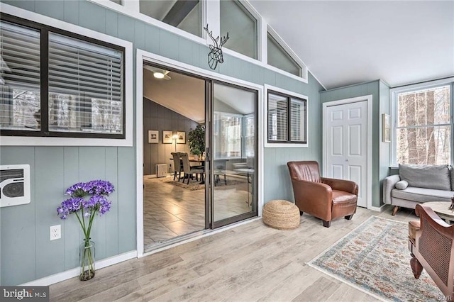 sitting room with heating unit, wood finished floors, and vaulted ceiling