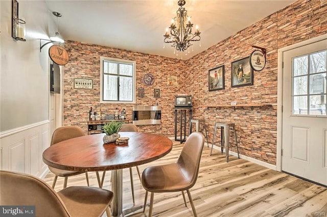 dining space with plenty of natural light, a notable chandelier, wood finished floors, and wainscoting