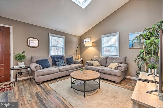 living room with vaulted ceiling with skylight, wood finished floors, and baseboards