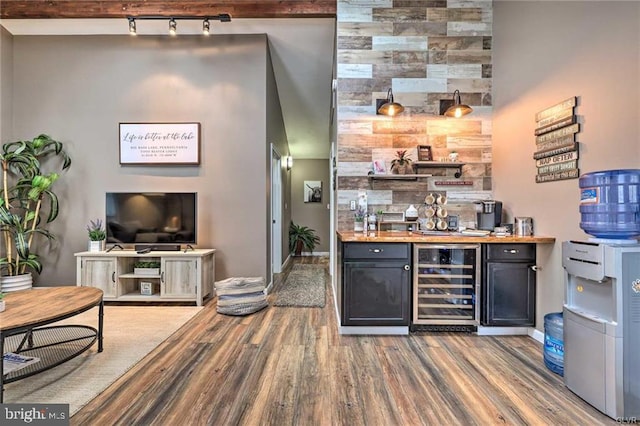 bar featuring beverage cooler, a bar, baseboards, and wood finished floors