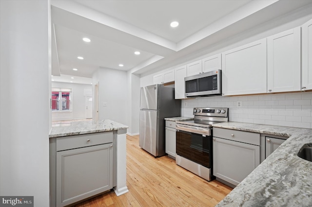 kitchen featuring light stone counters, light wood-type flooring, tasteful backsplash, and stainless steel appliances