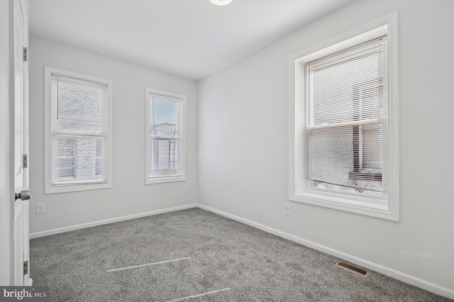 carpeted spare room featuring visible vents and baseboards