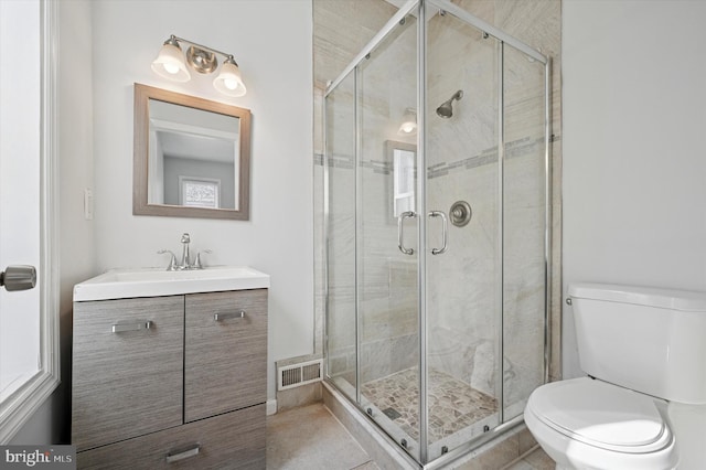 bathroom featuring vanity, toilet, visible vents, and a stall shower