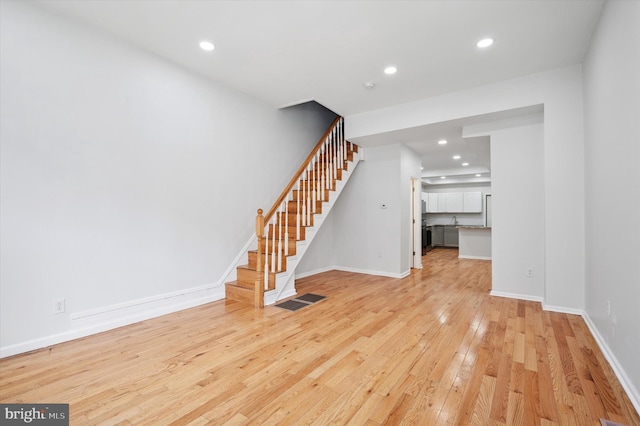 unfurnished living room with recessed lighting, stairs, and light wood finished floors