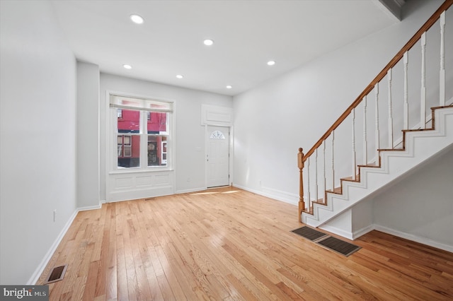 entrance foyer featuring visible vents, baseboards, stairway, and hardwood / wood-style flooring