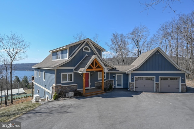 craftsman house with cooling unit, a garage, stone siding, aphalt driveway, and board and batten siding