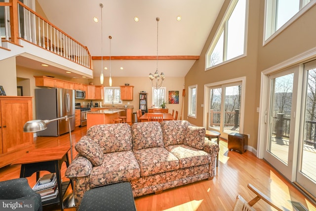 living area with light wood finished floors, visible vents, baseboards, a notable chandelier, and high vaulted ceiling