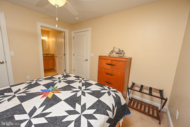 bedroom featuring ensuite bath, a ceiling fan, baseboards, and a sink