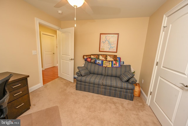 living area with carpet flooring, baseboards, and ceiling fan