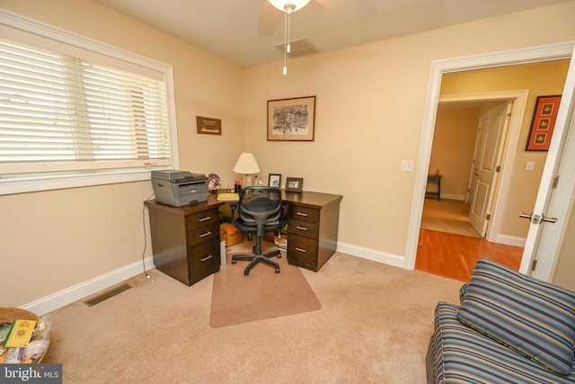 office area featuring light colored carpet, a ceiling fan, visible vents, and baseboards