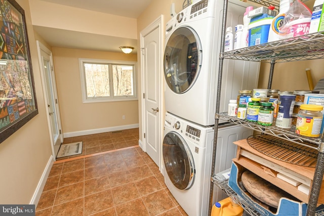 washroom featuring tile patterned floors, baseboards, laundry area, and stacked washing maching and dryer