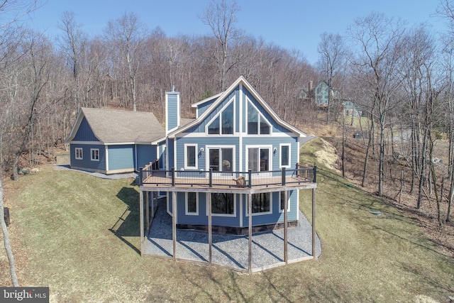 rear view of house featuring a deck, a yard, a patio area, and a chimney