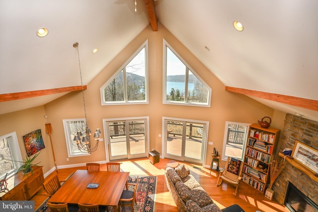 living room featuring a ceiling fan, wood finished floors, high vaulted ceiling, beamed ceiling, and a large fireplace